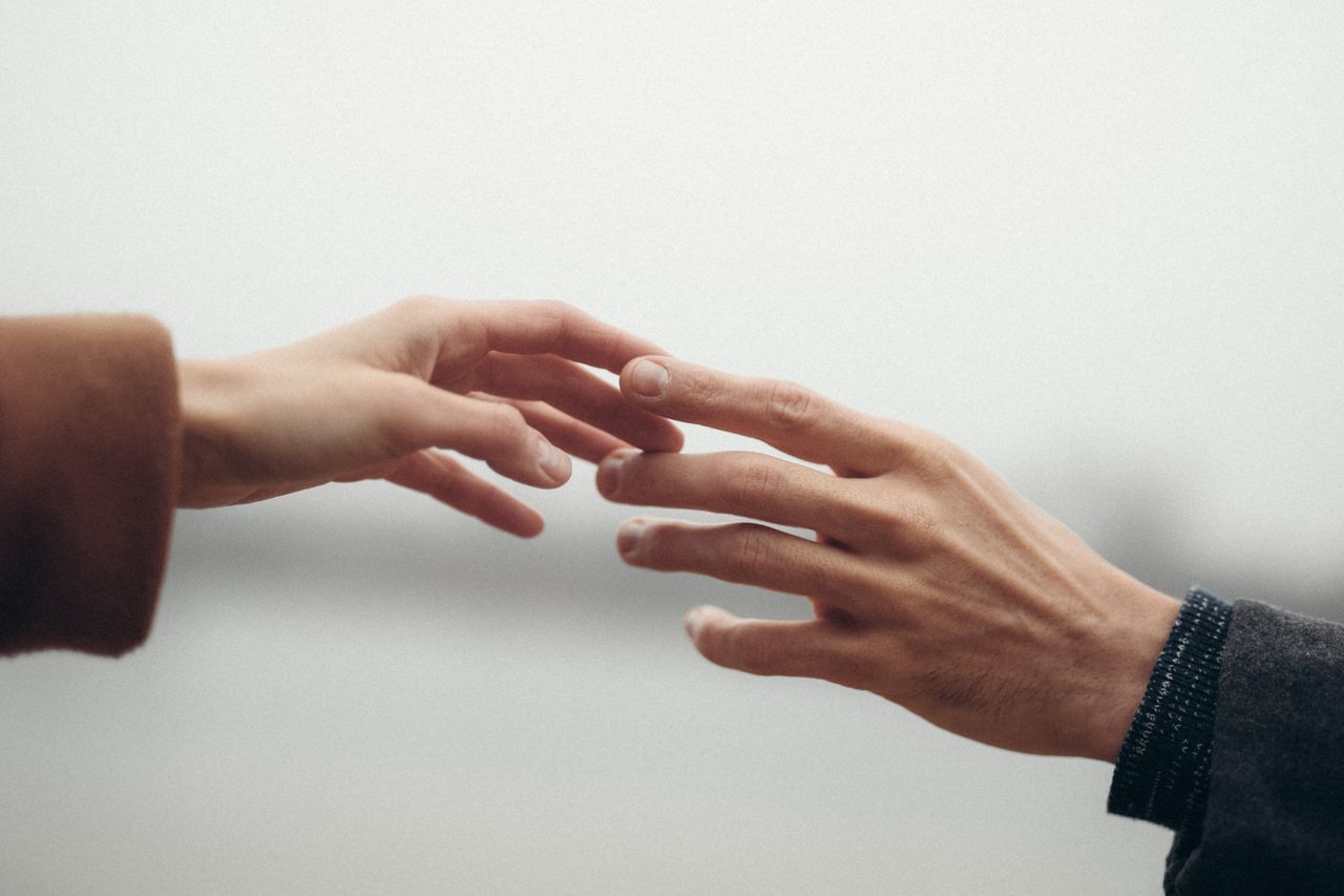 Two hands reaching out, symbolizing connection and intimacy.