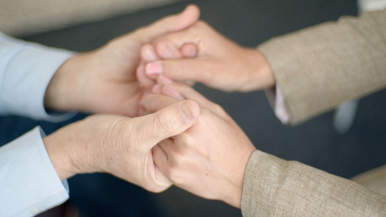 A heartfelt close-up showing a couple holding hands, symbolizing support and togetherness.